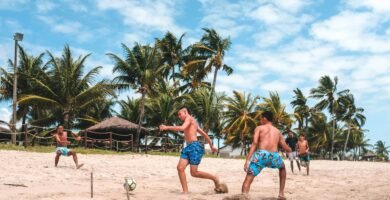 several men playing football on beach sand